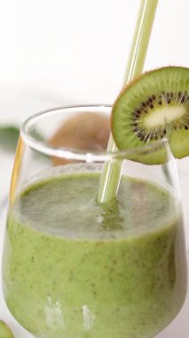 Cam pipetli kivi kokteyli içiyorum. Dikey video. Yakın plan..