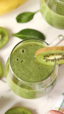 Cam pipetli kivi kokteyli içiyorum. Dikey video. Yakın plan..