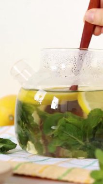 El, ev yapımı bitki çayını limon ve nane şekeriyle karıştırıyor. Dikey video. Yakın plan..