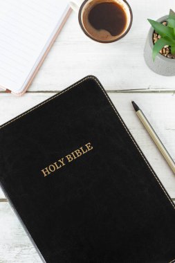 Üzerinde defter ve bir fincan kahve olan kutsal Hıristiyan İncil kitabı. Üst Manzara. İncil okuma, İncil kavramı..