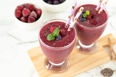 Ahududu böğürtlenli meyve püresi, chia tohumu ve beyaz mutfak masasında taze nane. Sağlıklı yaz karışımı..