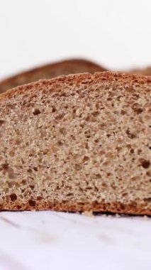 Beyaz mutfak masasında tam buğday ekmeği dilimi. Dikey video. Yakın plan..