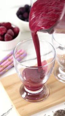 Böğürtlenli buzlu içeceği bardağa dolduruyorum. Dikey video.