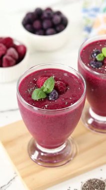 Ahududu böğürtlenli smoothie ve chia tohumu ve naneli saman koyarsanız elinizi kaldırın. Dikey video. Yakın plan..