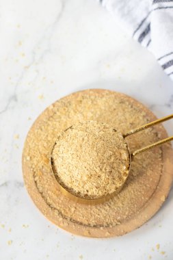 Besleyici maya tanecikleri ölçü kabında. Üst masa manzaralı. Peynir yerine, vejetaryen yemeği..