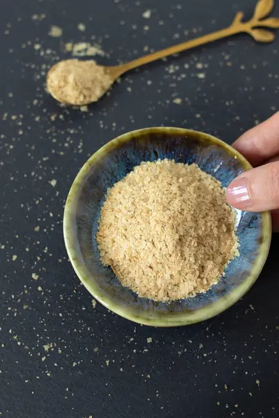 El, içinde besin maya taneleri olan bir kase tutuyor. Üst Manzara. Sağlıklı vejetaryen peyniri.