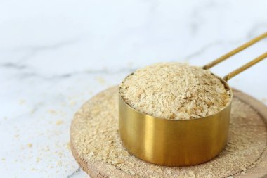 Beyaz mutfak masasındaki ölçü kabında besleyici maya. Yakın plan. Boşluğu kopyala.