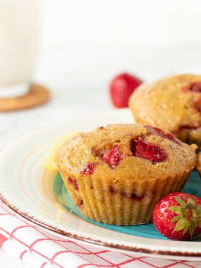 Arka planda bir bardak sütle birlikte bir tabakta ev yapımı çilekli kek. Yakın plan..