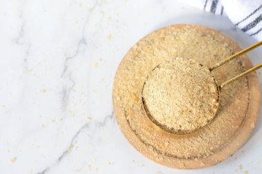 Beyaz mutfak masasındaki ölçü kabında besin değeri olan maya taneleri. Üst Manzara. Boşluğu kopyala.