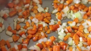 Kızartma tavasında doğranmış soğan ve havuç pişirmek ve sıcak sebze yağı. Yakın plan..