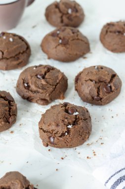 Beyaz parşömen kağıdında bir fincan sütle çikolatalı kurabiyeler. Sağlıklı ev yapımı vejetaryen tatlı..