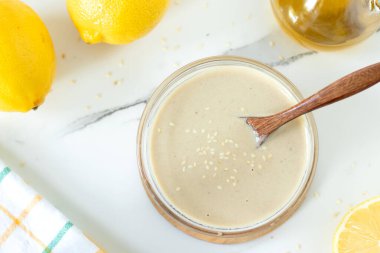 Tahini soslu beyaz sos ve tahta kaşıklı bir kasede limon. Üst görünüm.