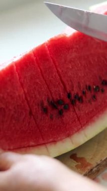 Elin mutfakta karpuz dilimleri kesiyor. Dikey video. Yakın plan..