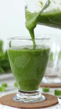 Bardağa yeşil smoothie dolduruyorum. Dikey video. Sağlıklı detoks karışımı..