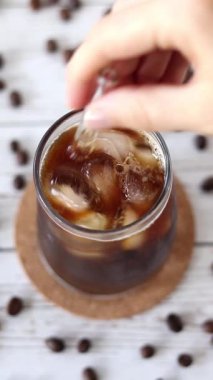 Elim buzlu kahveyi pipetle karıştırıyor. Dikey video. Üst görünüm.