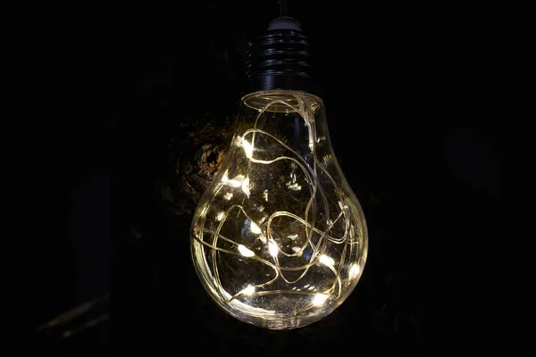 Decorative light bulb with lamps in the middle. Beautiful light bulb glows in the dark. Selective focus.