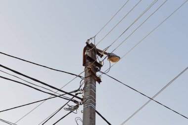 Street cement lamppost with cables on sky background. 