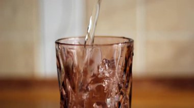 Kahverengi bir cam şişeye su dök..