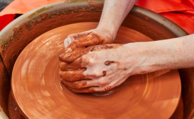 Çamur çömlek elleri yakın çekimde tekerlek el sanatları üzerinde çalışıyor. Clay çanak çömlek yapıyor. Potter elleri. Kırmızı kil ile çalışmak. 