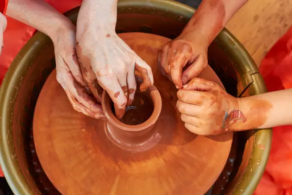 stock image Teaching a child to make pottery from red clay. Clay pottery hands close up working on wheel handcrafts. Clay crockery making. Working with red clay. 