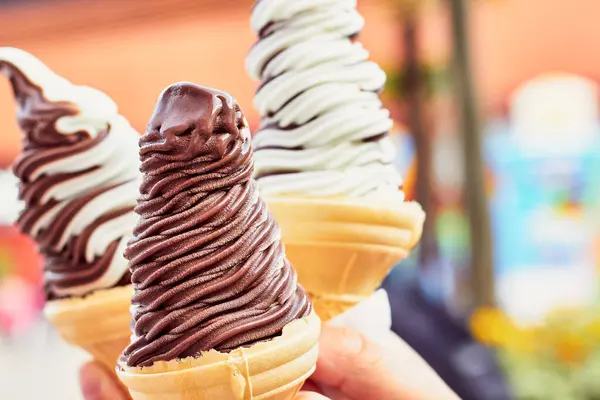 Three ice cream. Chocolate vanilla ice cream in waffle cups in hands.