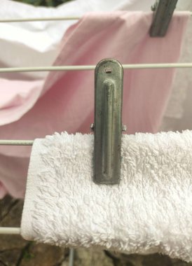Metal Clothespin 'in yakın çekimi Beyaz Havluyu Yumuşak Pembe Arkaplan- Her Gün Ev Hayatı