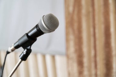 Klasik bir mikrofon, spot ışıklarıyla aydınlatılmış, büyüleyici bir performans veya kayıt için hazır, müziğin, konuşmanın ve eğlencenin özünü çağrıştırıyor.         