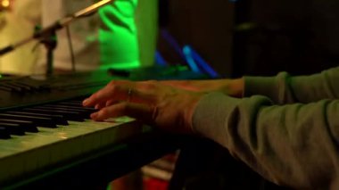 Klavyeci elleri canlı müzik konserinde yeşil ışıkta synthesizer 'da performans sergiliyor.