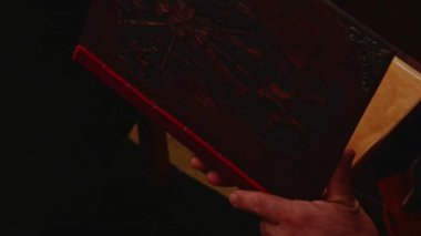 Ortaçağ tarihinin yeniden canlandırması. İnsanlar ortaçağ ahşap kapaklı ve oymalarla süslenmiş bir kitabı açar.