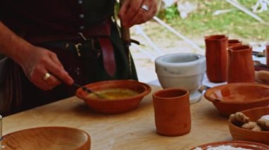Ortaçağ canlandırması. Ortaçağ giysili bir adam kasede yumurta çırpar ve yemek hazırlamak için biraz baharat ekler.