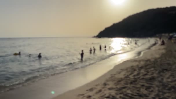 明るく認識できない人々と日没のバックライト付きのパノラマビーチ — ストック動画