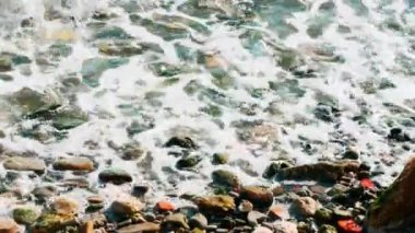 Sahilde dalgalar sahile vururken deniz kıyılarının çakıl taşlarıyla çekilmesi.
