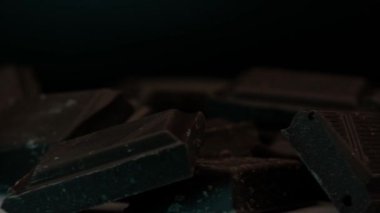 Yakından görülen renkli ışıklarla aydınlatılmış bir tepside koyu çikolata parçalarının dönüşümü