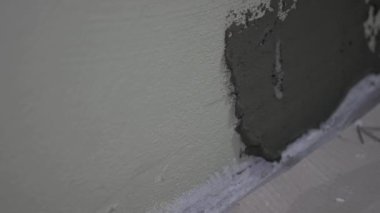 Yakın çekim işçisi aletleri kullanarak duvara çimento ya da yapıştırıcı sürer. DIY iç dekorasyon