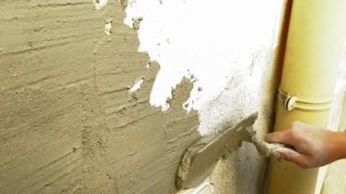 Yakın çekim ev inşaatı, duvar tadilatçısı el yapımı çimento veya spatulayla duvara sıva serpiştirilmiş sıva. İnşaat işi, DIY, ev onarımı ve yenileme