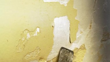 İnşaat işçilerinin ev onarımı için duvardan eski alçıyı spatulayla kazıdıkları yakın çekim. Ev yenileme işi, inşaat işi, DIY