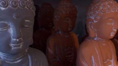 Bir mağazadaki çeşitli Buda seramik heykellerinin olduğu rafı ev ya da bahçe dekorasyonu olarak kapatın. Dini dekorasyonlar, meditasyon ve maneviyat kavramı