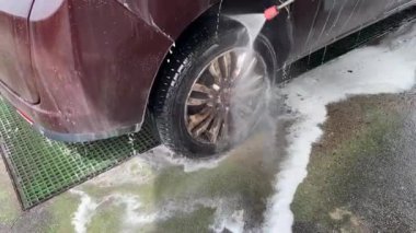 Köpüğü temizlemek için araba yıkamada bir jet tarafından püskürtülmüş parlak siyah bir arabanın görüntüsü. Profesyonel oto yıkama, hijyen ve araba yıkama faaliyetleri.