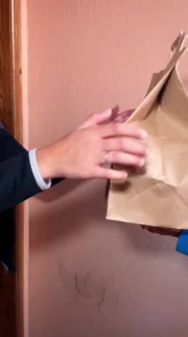 Teslimatçı müşteriye sipariş edilen öğle yemeğini içeren paketi verir. Yemek teslimatı.