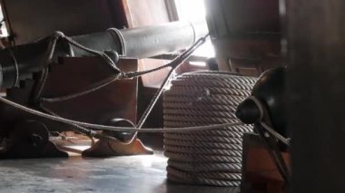 18. yüzyılın eski bir İspanyol yelkenli gemisinin güvertesinin altında sıra sıra dizilmiş halat ve toplar. Tarihi donanma savaş ekipmanları