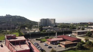 Tepesi olan yeşil bir İtalyan şehrindeki bir otoparkın üzerinde 4K 'lık İHA atışı. Şehir, doğa ve şehir İHA görüntülerini parketti