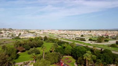 Şehir parkının panoramik görüntüsünü ve büyük yeşil çimenleri gösteren 4K drone görüntüsü. İnsansız hava aracı videosu şehri ve doğayı parkediyor