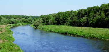 Gün boyunca yeşil ağaçların ve nehirlerin doğasıyla çevrili geniş bir nehir.