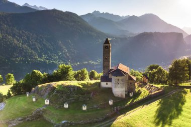 Aerial view of a church in Rossura in Switzerland during a sunset in a summer day, Rossura, Faido, Leventina, Switzerland.  clipart