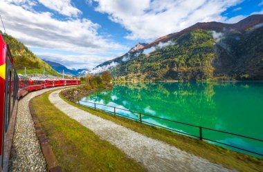 İsviçre Alplerinde Miralago Gölü boyunca Bernina Ekspres Yolu 'ndaki Kızıl Tren, İsviçre Graubunden kantonunda Val Poschiavo. 