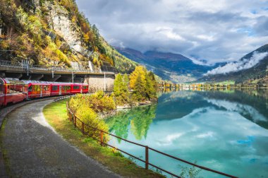 İsviçre Alplerinde Miralago Gölü boyunca Bernina Ekspres Yolu 'ndaki Kızıl Tren, İsviçre Graubunden kantonunda Val Poschiavo. 