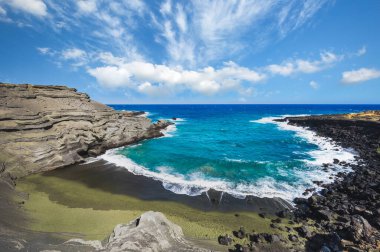Hawaii Büyük Adası 'ndaki Papakolea Yeşil Kum Kumsalı. Turkuaz dalgaları, volkanik kayalıklar ve parlak mavi gökyüzünün altında nadir bulunan olivin kumları..