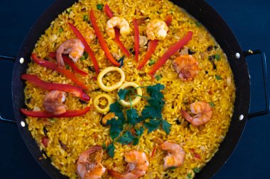 İspanya 'nın klasik yemeği, koyu mavi arka plan görünümlü geleneksel tavada deniz ürünleri paella.