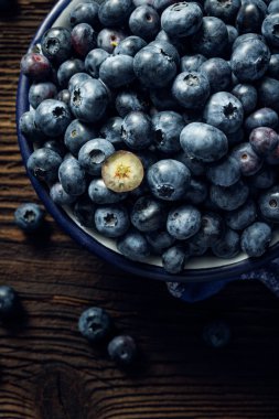 Tahta bir masada, bir kasede olgun yaban mersini, yakın görüş.