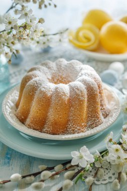 Paskalya limonlu kek, Bahar çiçekleriyle süslenmiş bir şenlik masasına pudra şekeri serpiştirilmiş Babka, yakın görüş.